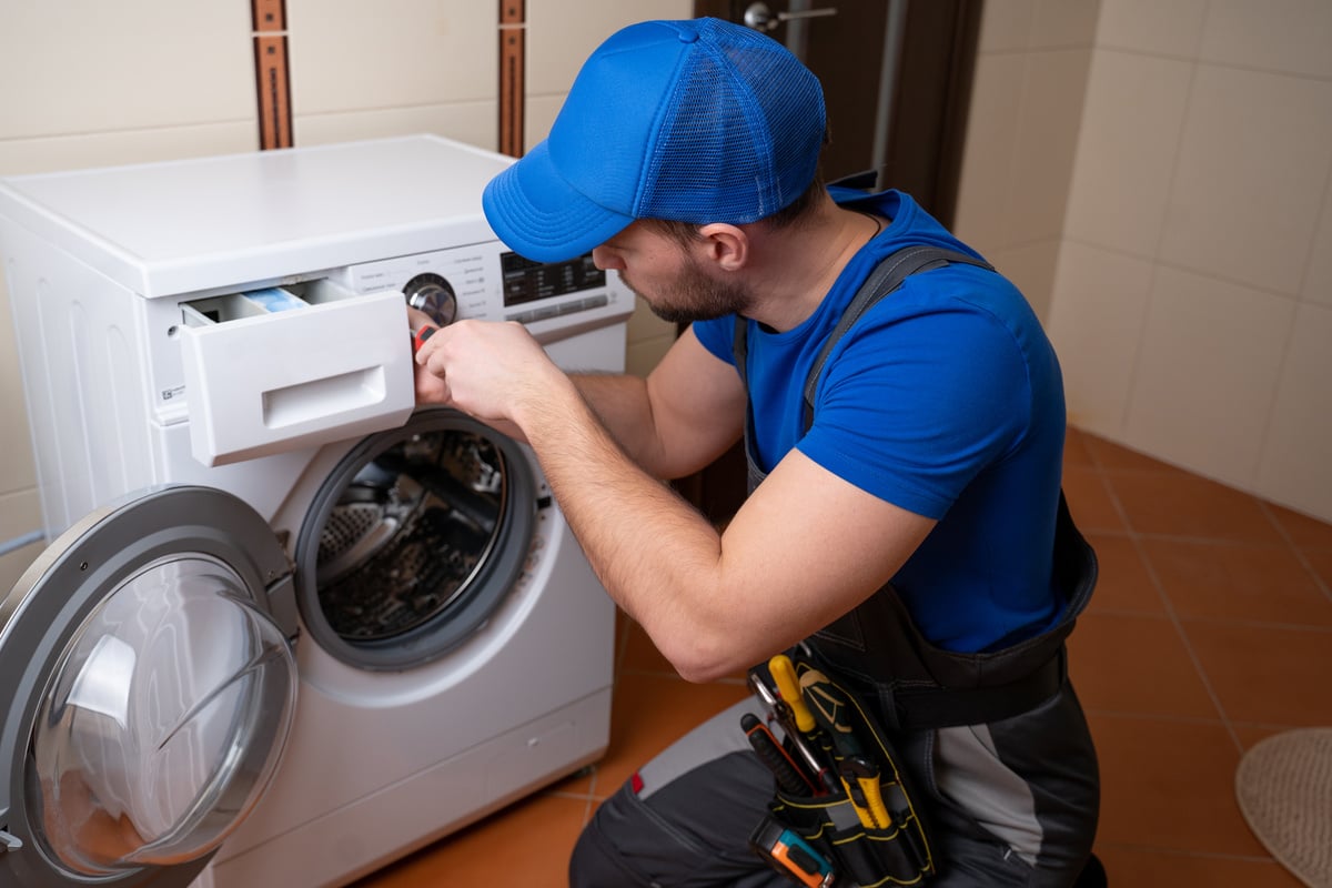 Worker repairing washing machine in laundry room