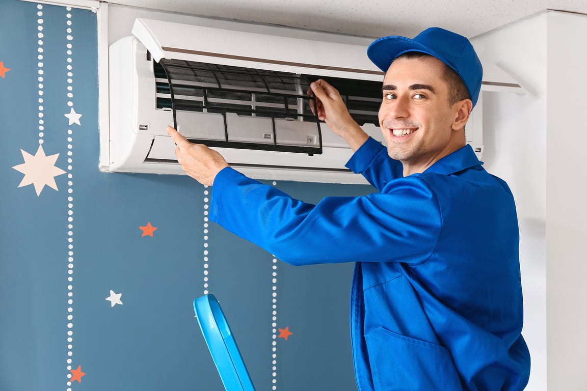 Male Technician Repairing Air Conditioner Indoors